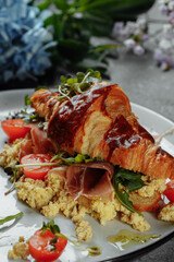 Delicious croissant sandwich with ham, cheese and scrambled eggs on plate served