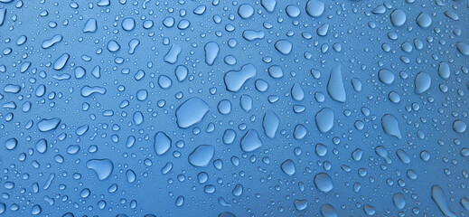 A drop of water on the hood of the car. Water beads after rain or car wash on blue paint surface.