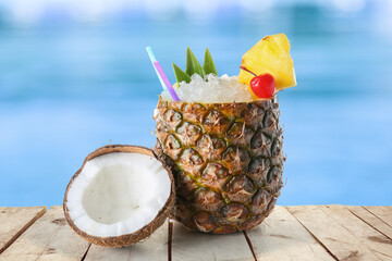 Cold Pina Colada cocktail in fresh pineapple on edge of swimming pool