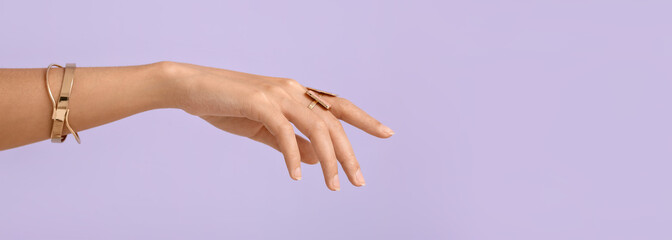 Hand of beautiful woman wearing stylish jewellery on lilac background with space for text