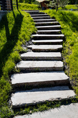 A staircase made of concrete steps in the park, urban landscape design, steps rise up, a path of their concrete, a sidewalk and a green lawn.