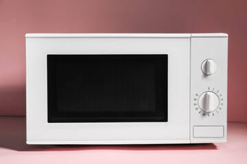 Obraz premium New modern microwave oven on pink background