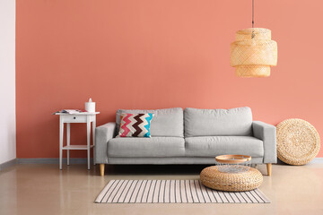 Fototapeta na wymiar Comfortable sofa and stylish lamp near pink wall