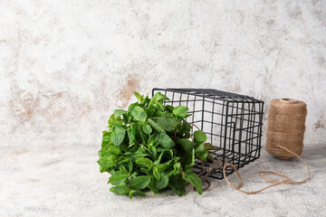 Basket with mint leaves on light background