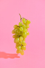 Ripe green grapes on pink background