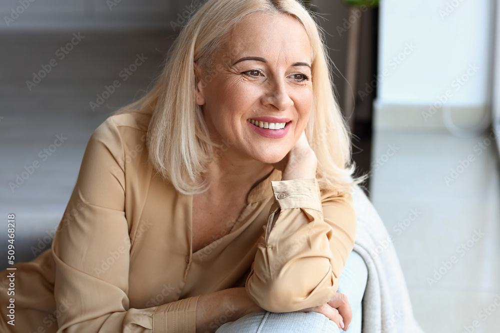 Sticker Morning of beautiful mature woman sitting on sofa near window