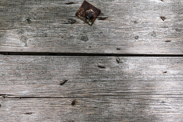 An old and cracked wooden panels with rusty nails, nut and bolt in it as a background