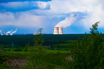 Evening sunset sky scene with dramatic clouds. A nuclear power plant in a field behind a forest