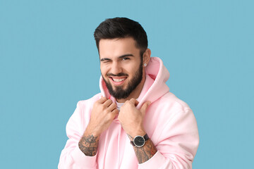 Smiling bearded man winking on blue background