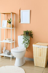 Interior of restroom with toilet bowl, shelving unit and laundry basket