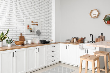 Interior of light kitchen with counters, utensils and stools