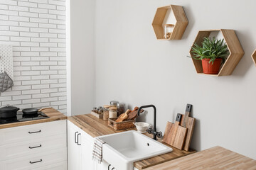 Counters with kitchen utensils, sink and food near light wall