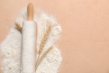 Rolling pin and wheat flour on color background