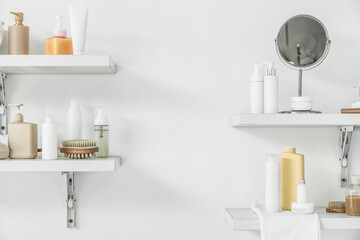 Shelves with bath accessories hanging on light wall