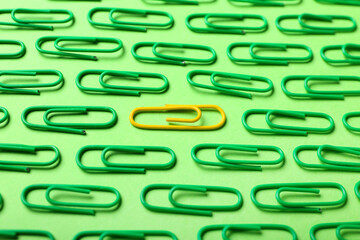Yellow and green paper clips on color background