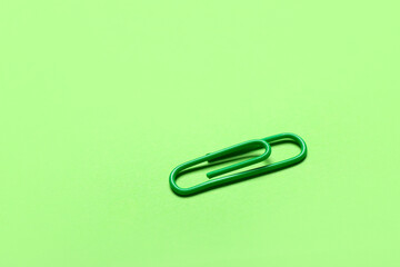 Green paper clip on color background