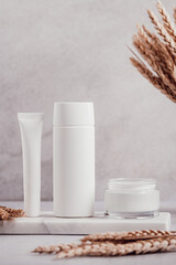 White blank cosmetic bottles and wheat decor for mock up on white marble tray