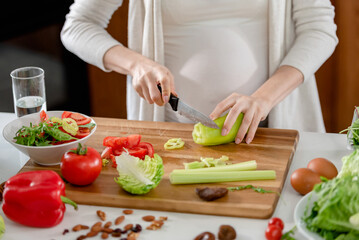 Young pregnant woman preparing healthy food with fruit and vegetables