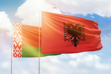 Sunny blue sky and flags of albania and belarus