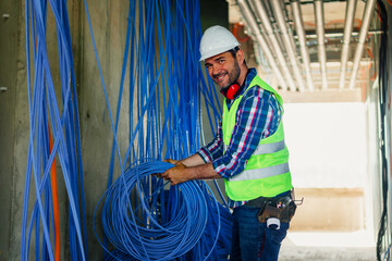 A skilled electrician in construction checking cables for building electric network.