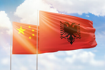 Sunny blue sky and flags of albania and china