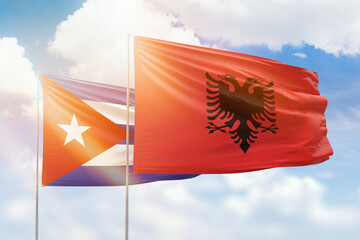 Sunny blue sky and flags of albania and cuba