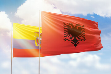 Sunny blue sky and flags of albania and ecuador