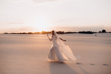 Fototapeta na wymiar young woman in white dress walking on the beach