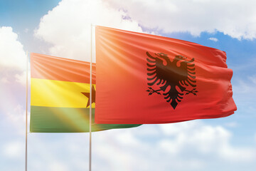 Sunny blue sky and flags of albania and ghana