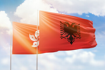 Sunny blue sky and flags of albania and hong kong