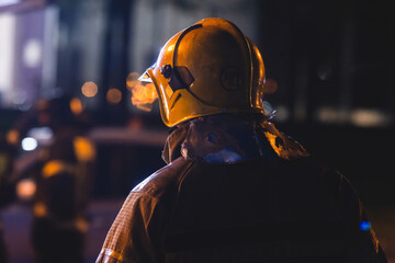 Group of fire men in uniform during fire fighting operation in the night city streets, firefighters...