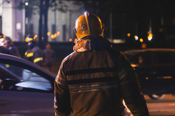 Group of fire men in uniform during fire fighting operation in the night city streets, firefighters...