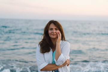 Portrait of a happy young woman on a background of beautiful sea. The girl looks at the magical sea. Freedom and happiness