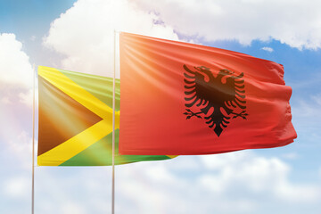 Sunny blue sky and flags of albania and jamaica