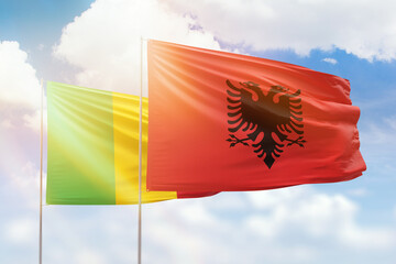 Sunny blue sky and flags of albania and mali