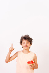 Boy eating a watermelon and pointing up, summer vacation. White background with copy paste