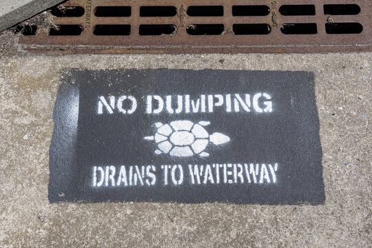 No Dumping Drians to Waterway with turtle spray painted on paving by storm drain at curb or road