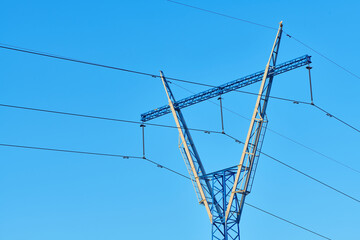 High voltage electricity tower with power line against blue sky. Overhead electric power line with...