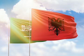 Sunny blue sky and flags of albania and saudi arabia