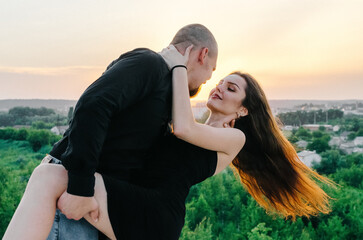 man and woman in black clothes hugging at sunset