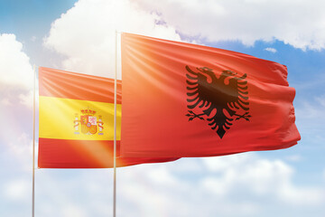 Sunny blue sky and flags of albania and spain