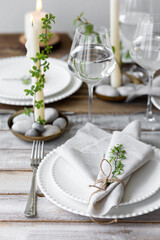 Rustic zero waste wedding decor with natural elements. Wooden table, candles, linen napkins, branches with green leaves. Eco-friendly decoration for the special dinner. Romantic and cozy place