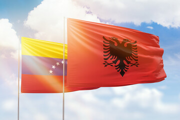 Sunny blue sky and flags of albania and venezuela