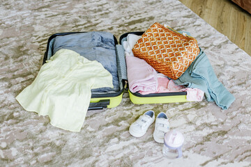 Children's travel suitcase with clothes and shoes on floor of room. Vacation with children concept