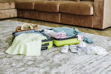Children's travel suitcase with clothes and shoes on floor of room. Vacation with children concept.