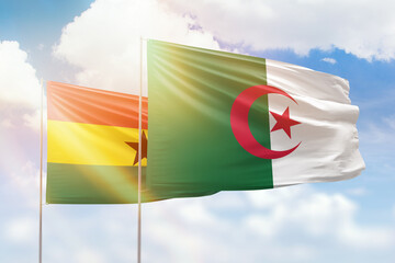 Sunny blue sky and flags of algeria and ghana