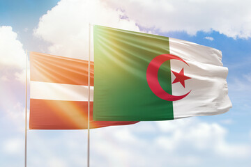 Sunny blue sky and flags of algeria and latvia