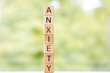 Anxiety word is written on wooden cubes on a green summer background Closeup of wooden elements