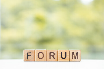 Forum word is written on wooden cubes on a green summer background Closeup of wooden elements