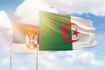 Sunny blue sky and flags of algeria and serbia